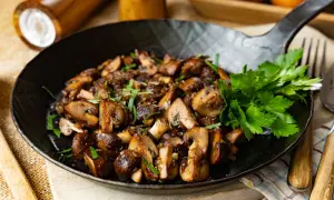 Gebratene Champignons in einer Pfanne, garniert mit frischer Petersilie. Ein köstliches Gericht, das zum Genießen einlädt.