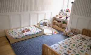 A baby sleeps on a floor bed with animal print sheets, showcasing floor bed safety in a nursery.