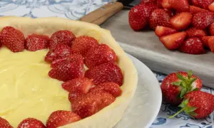 Une délicieuse tarte aux fraises et crème pâtissière, prête à être dégustée. Des fraises fraîches garnissent généreusement cette pâtisserie.