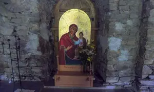 Ikona Matki Boskiej z Dzieciątkiem w kamiennej niszy cerkwi w Łopience. Obok świecznik.