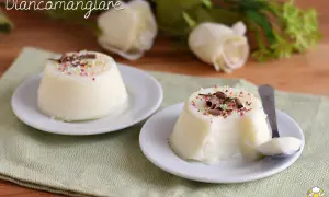 Biancomangiare ricetta: due dolci al cucchiaio guarniti con codette colorate e scaglie di cioccolato, su piattini bianchi e tovagliolo verde.