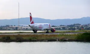 Samolot Czech Airlines kołuje na pasie startowym lotniska na Korfu. W tle góry i zabudowania.