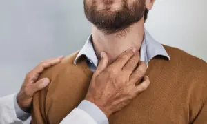 Lekarz bada szyję pacjenta, dotykając jego jabłka adama.