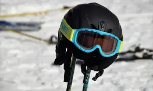 Czarny kask narciarski damski z niebieskimi goglami i żółtym paskiem, gotowy na stok. Szyba fotochromatyczna dopasuje się do warunków.