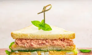 Tramezzini veloci con tonno, uova e lattuga, guarniti con basilico fresco. Perfetti per un pasto rapido e gustoso.