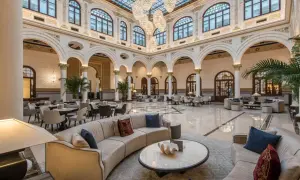 Elegante lobby del spa hotel Miramar, con sofás curvos, mesas y grandes lámparas de araña bajo un techo de cristal.
