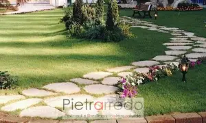 Un sentiero sinuoso di pietre irregolari attraversa un prato verde, creando un passaggio suggestivo nel giardino.