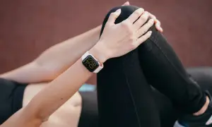 Kobieta w sportowym stroju, z zegarkiem na ręce, pokazuje, jak sparować zegarek z telefonem.