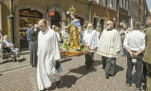 Procesja z figurą Matki Boskiej. Czy w Boże Ciało trzeba iść do kościoła? Wierni niosą figurę ulicą, niektórzy w strojach duchownych.