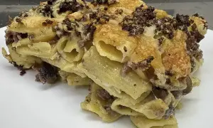Un invitante piatto di pasta al forno, la ricetta della nonna, con pasta rigata, ragù e formaggio filante.