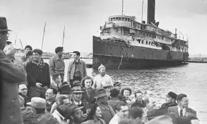 Folk samlas vid en skadad båt, en scen som speglar en del av israel historia.