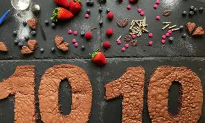 Zahlentorte mit Biskuitboden in Form einer 10, dekoriert mit Erdbeeren, Blaubeeren und Schokoladenherzen.