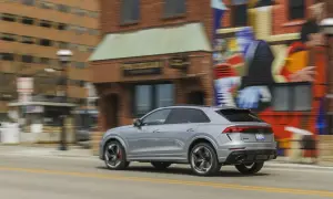 Srebrny Audi RS Q8 pędzi ulicą obok kolorowego muralu. Sprawdź aktualną audi rsq8 cena i możliwości tego SUV-a.