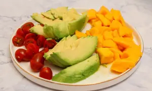 Plato con ensalada de mango y aguacate, tomates cherry cortados por la mitad y aguacate en láminas.
