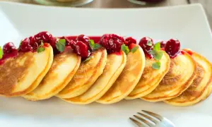 Złociste placuszki, idealne na śniadanie, polane wiśniowym sosem i udekorowane listkami mięty. Pyszny przepis na pancake!