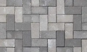 Szary bruk z kostki betonowej ułożony w cegiełkę. Dowiedz się, jak usunąć zaprawę z kostki brukowej, by odzyskać jej pierwotny wygląd.