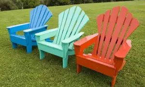 Tres sillas de madera de estilo Adirondack, pintadas de azul, verde menta y naranja, listas para disfrutar del exterior. ¡Pintar sillas de madera sin lijar es fácil!