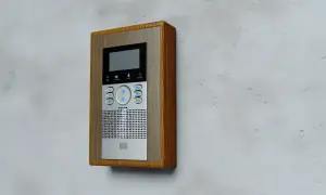 Nowoczesny domofon z drewnianą ramką. Dowiedz się, jak otworzyć drzwi domofonem, wybierając odpowiedni numer mieszkania.