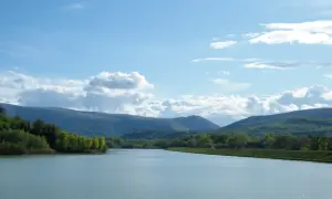 Vasto lago delle grazie con colline verdi e cielo azzurro con nuvole bianche.
