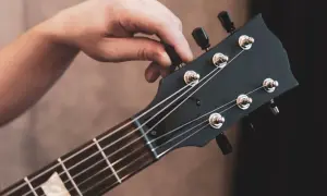 Dłoń kręci kluczem, by nastroić gitarę. Idealne brzmienie czeka!