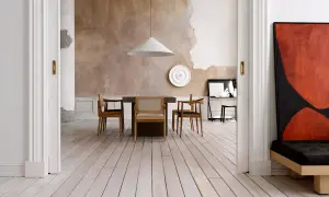 Sala da pranzo con pareti a pittura a calce grezza, tavolo in legno e sedie moderne. Un quadro astratto rosso e nero domina lo spazio.