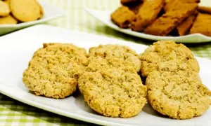 Gyllene havrekakor på en vit tallrik, perfekta för ett enkelt havrekakor recept. I bakgrunden syns fler kakor.