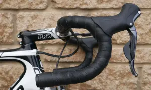 Czarna owijka na kierownicę roweru szosowego z subtelnym wzorem. Widoczna manetka Shimano i mostek PRO.