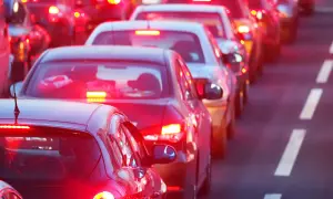 File d'attente de voitures, feux arrière rouges allumés, y compris le troisième feu stop obligatoire, créant une ambiance de fin de journée.