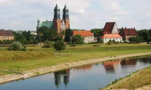 Widok na Ostrów Tumski w Poznaniu z katedrą i innymi zabytkowymi budynkami nad rzeką Wartą.