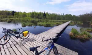 Dwa rowery na drewnianym pomoście nad wodą, otoczone zielenią. Idealne miejsce na odkrywanie tras rowerowych Białystok.