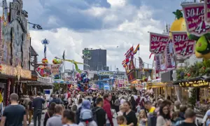 Buntes Volksfest mit vielen Menschen, Fahrgeschäften und Buden. Ein Hamburger-Stand ist nicht zu sehen, aber die Stimmung ist ausgelassen.