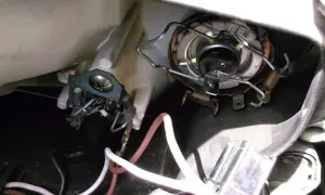 Wymiana żarówki przód Mitsubishi Colt. Widoczny mechanizm mocowania żarówki i przewody.
