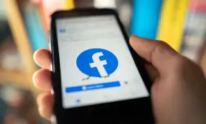 Dłoń trzyma smartfon z logo Facebooka. Chcesz wiedzieć, jak usunąć fb ale zostawić messengera?