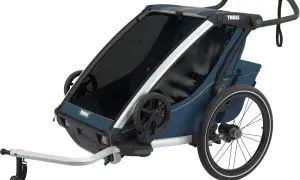 En blå Thule trailer med stora hjul och ett handtag, redo för äventyr med barnen.