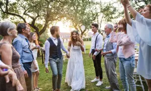 Ein glückliches Brautpaar, schick legere gekleidet, wird von seiner Familie im Garten gefeiert.