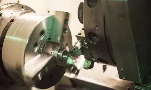 Precyzyjne toczenie aluminium na obrabiarce CNC. Metalowy element obraca się, a narzędzie precyzyjnie nadaje mu kształt.