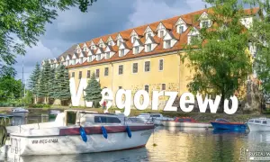 Węgorzewo: malowniczy widok na port z łodziami i zabytkową kamienicą. Idealne miejsce na rodzinne wycieczki, oferujące wiele atrakcji dla dzieci.