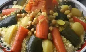Un plat coloré de recette couscous avec carottes, courgettes, pois chiches et pommes de terre.