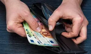 Ręce wkładają do portfela banknoty euro. Zarobione pieniądze po ciężkiej pracy lakiernika.