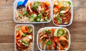 Vier Behälter mit Reis, Hähnchenbrust, Gurken- und Karottenstreifen – perfekt als pre workout meal für Energie.