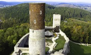 Zamek Krzyżtopór w Górach Świętokrzyskich, z charakterystyczną wieżą i murami obronnymi, otoczony jesiennym lasem.