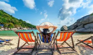 Relaks na plaży z widokiem na turkusowe morze i zielone wzgórza. Idealne miejsce, by odpocząć i zastanowić się, co robić w wakacje.