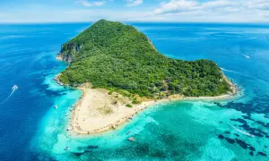 Malownicza wyspa Caretta Island na Zakynthos, z piaszczystą plażą i turkusową wodą, otoczona zielonymi wzgórzami.