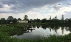 Łowisko Cicha Woda Niedrzwica Duża: spokojna tafla wody, przytulny domek i drewniany pomost.