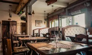 Wnętrze restauracji z drewnianymi stołami i wygodnymi kanapami. Na ścianie wisi model statku, nawiązujący do morskiego klimatu, jak w gdańskim bowke.