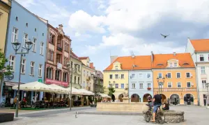 Kolorowy rynek w Gliwicach, idealne miejsce na weekendowe atrakcje. Ludzie siedzą w ogródkach kawiarnianych, a w tle widać zabytkowe kamienice.