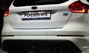Biały Ford Focus RS z podwójnym wydechem i niebieskim znaczkiem RS.