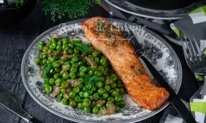 Filet de saumon poêlé servi avec une poêlée de petits pois et oignons, garnie de menthe fraîche. Une recette simple et savoureuse.