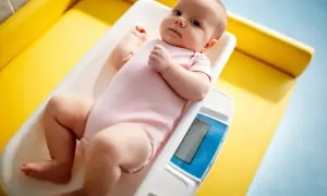 Malutkie dziecko w różowym body leży na wadze. Tak świat może widzieć noworodek, wszystko jest rozmazane, ale twarz dziecka jest wyraźna.