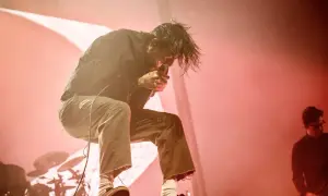Chino Moreno z Deftones na koncercie w Polsce, w ogniu czerwonych świateł, śpiewa z pasją.